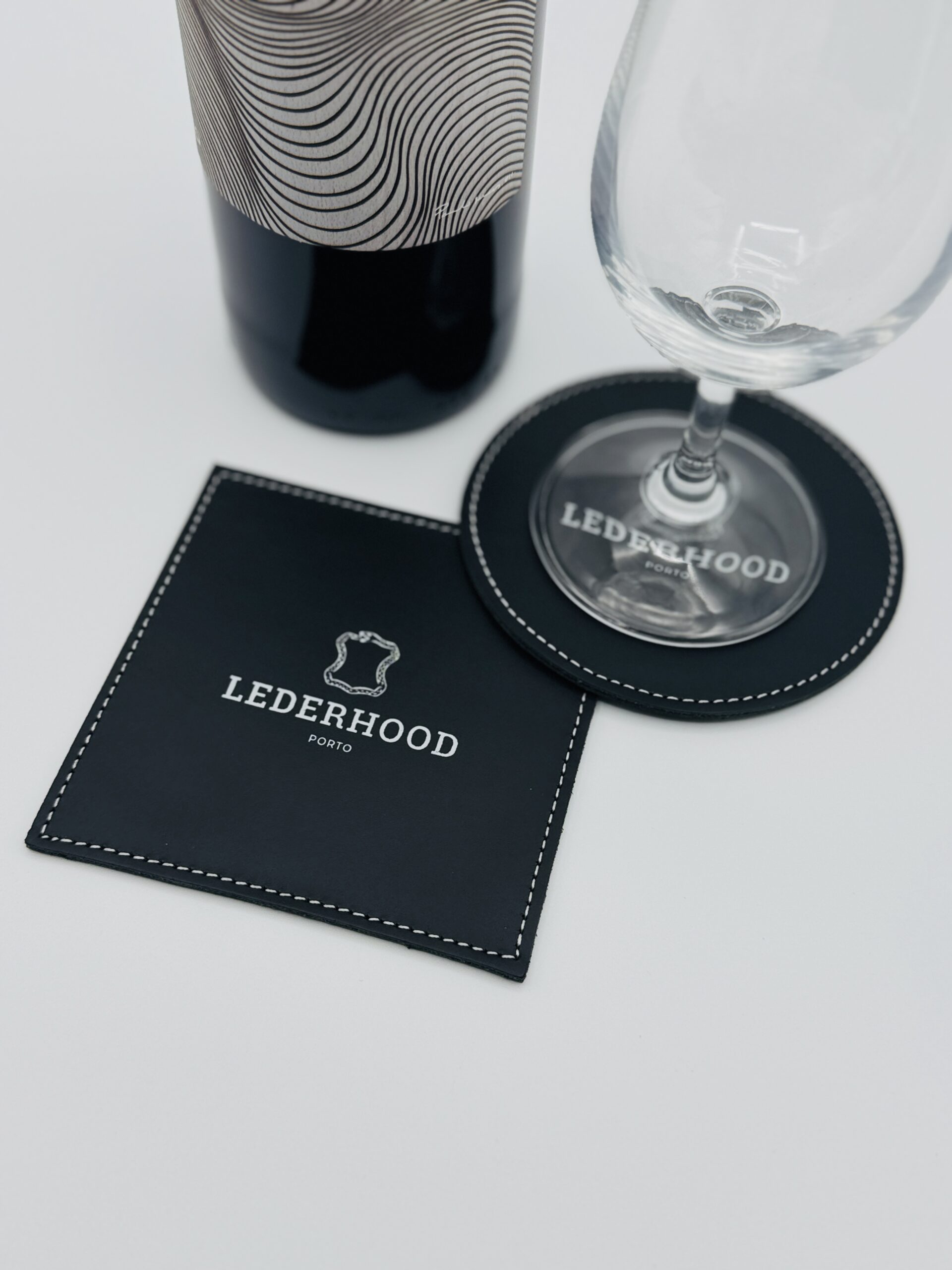Two classic black coasters, one round and one squared with a logo on the center
