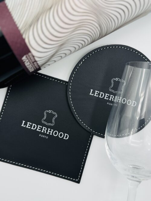 Two classic black coasters, one round and one squared with a logo on the center