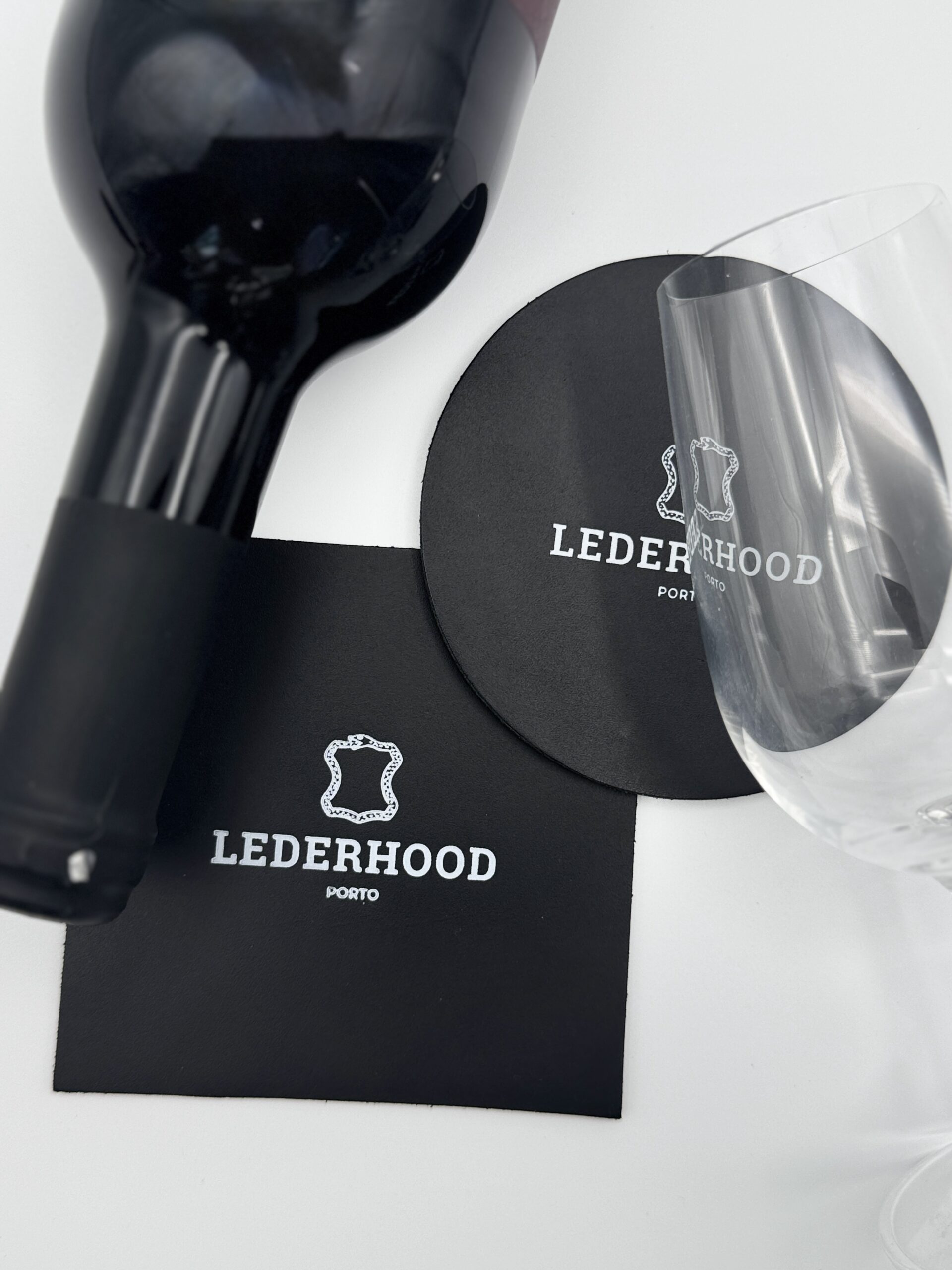 Two classic black coasters, one round and one squared with a logo on the center