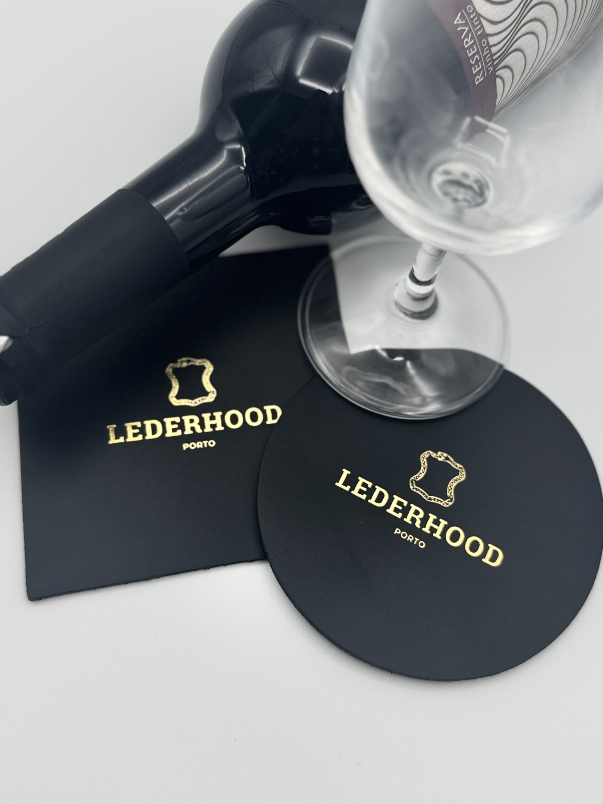 Two classic black coasters, one round and one squared with a logo on the center